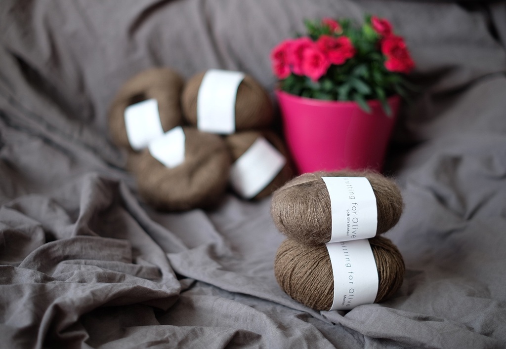 Мотки пряжи Knitting for Olive Soft Silk Mohair и Merino на сером фоне с розовым цветком | Skeins of Knitting for Olive Soft Silk Mohair and Merino yarn on grey background with pink flower