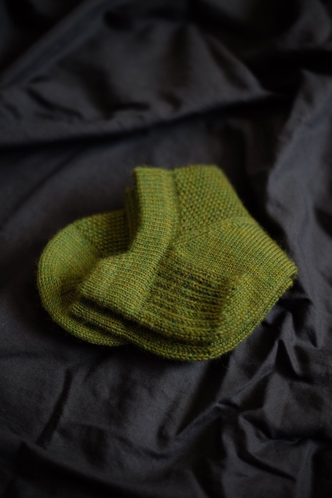 Close-up of green So Sporty Socks on black fabric, focusing on the heel and cuff detail.