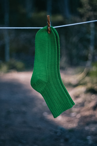 Hand knitted socks hanging on a clothesline in the woods
